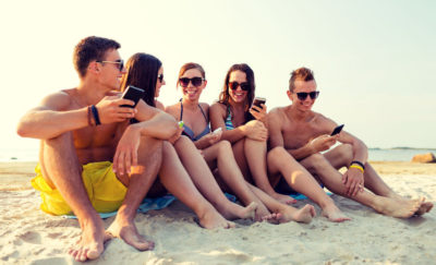 teens sitting together on the beach smiling