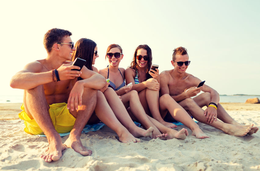teens sitting together on the beach smiling