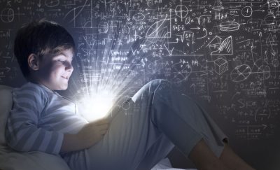 a photo of a kid looking at a tablet in bed, with mathematical concepts surrounding him, depicting the reality of digital technology in education