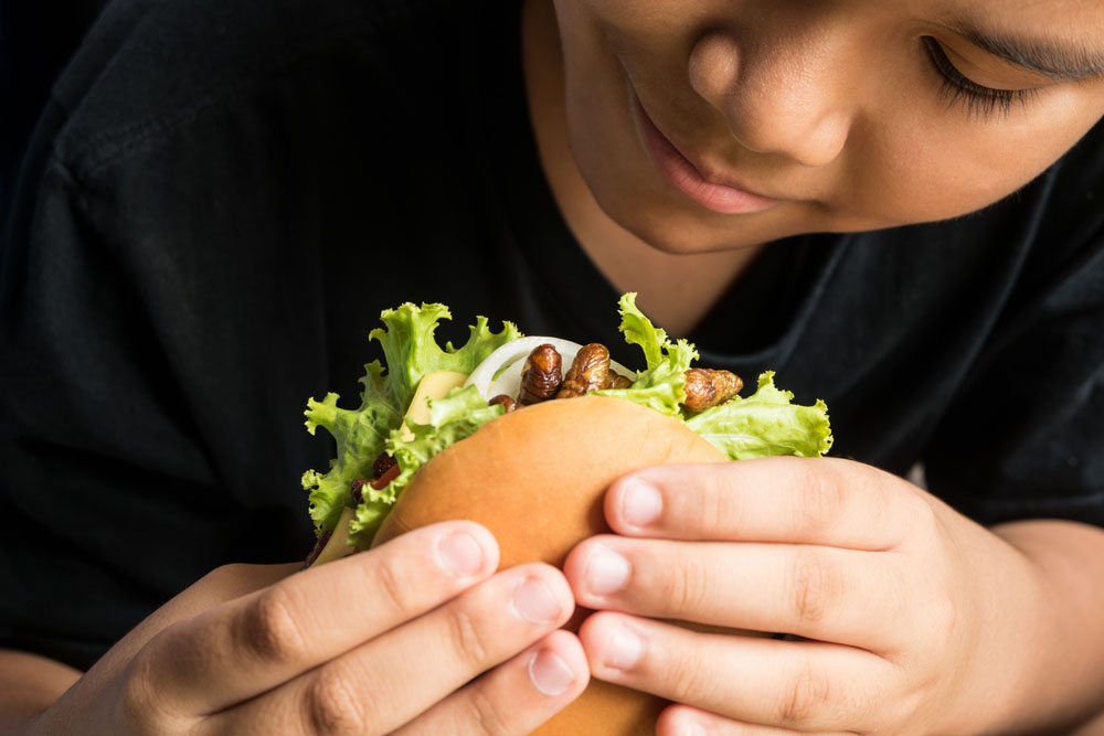 a close-up photo of a person eating one of the insect burgers in Switzerland