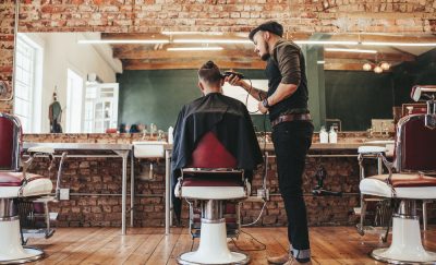 a photo of a barber shaving the head of a man's head inside a stylish barber shop while scientists discover a stem cell hair growth cure