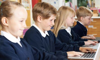 School children in uniforms working on computers with the help of personalized learning technology
