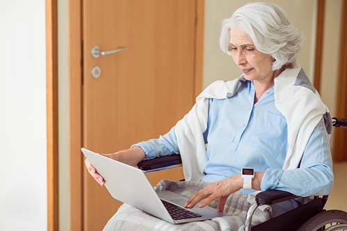 Senior in wheelchair with device on wrist
