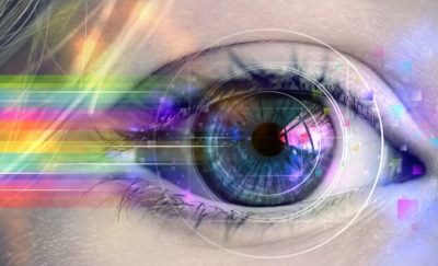 a close up photo of a woman's eye with a rainbow of colors streaming from it amid developments in technology related to anesthesia for eye surgery