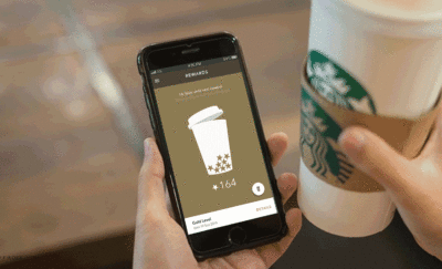 smartphone with starbucks mobile payment app open and cup of coffee