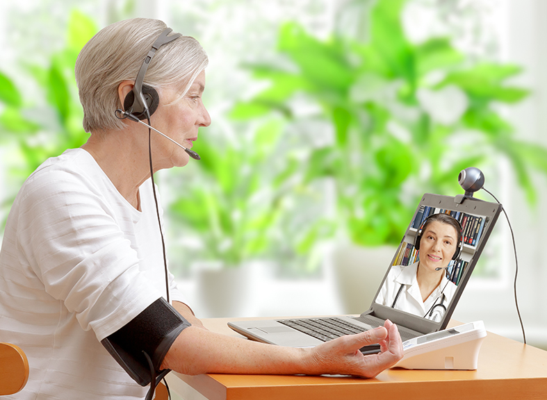 elderly woman using blood pressure monitor while teleconferencing with her doctor