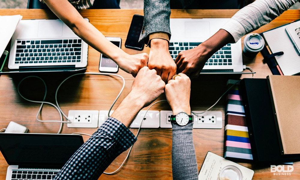 a team of five doing a fist bump over an office table showing competitive market dynamics