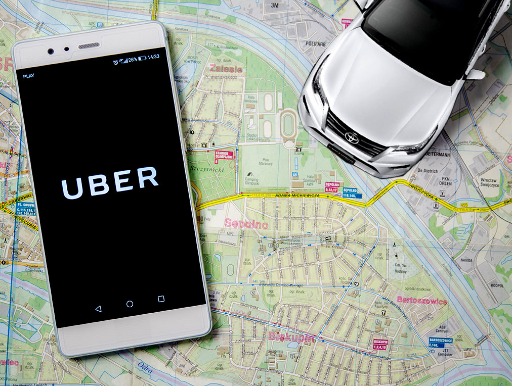 investing in uber, smartphone with the uber logo and car over a map