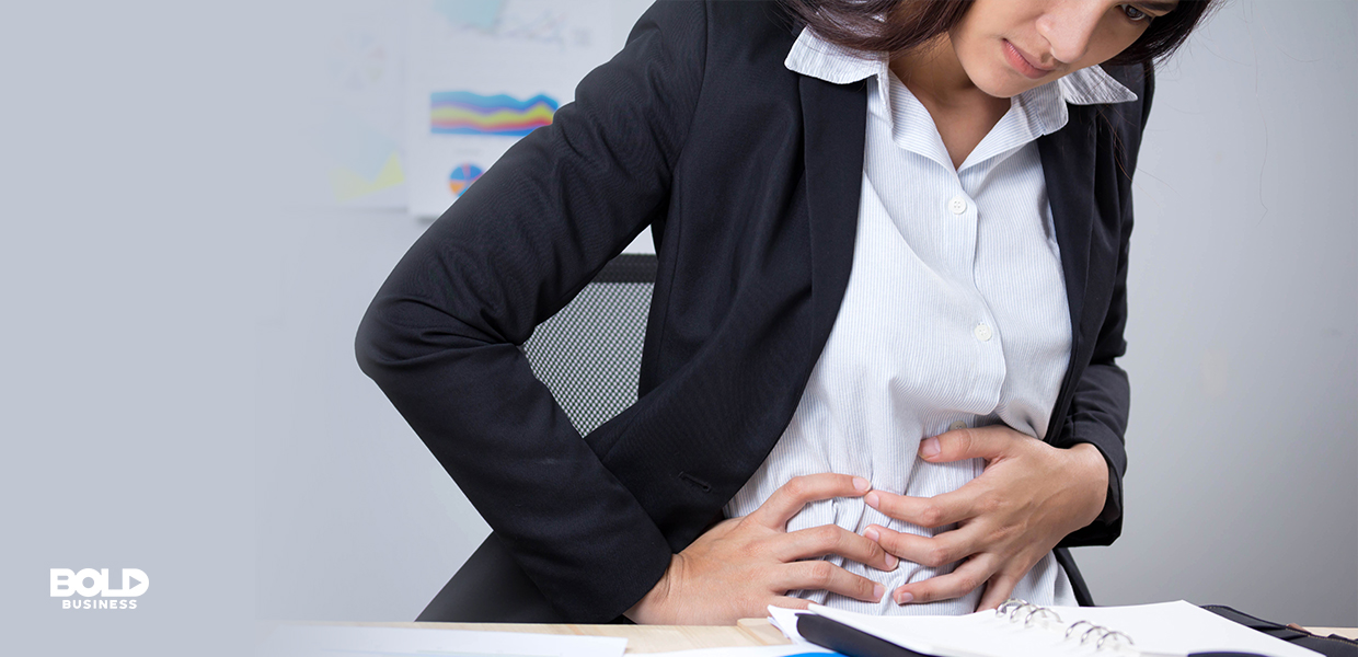 a photo of a woman clutching her stomach in pain amid the rise of new insights concerning the link between irritable bowel symptoms and the gut-brain connection