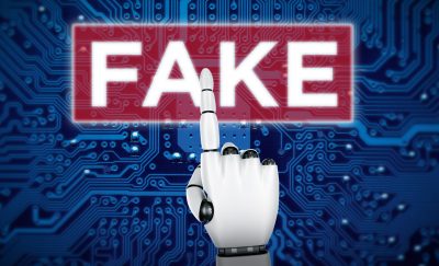 photo of an AI robot's hand pointing to the word FAKE embossed on a magnified part of a microchip amid fake reviews online